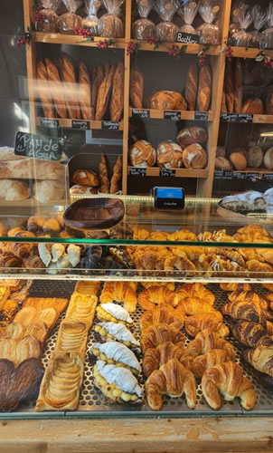 Expositor de la panadería Orriols con una selección de bollería y panes artesanales varios en la estantería
